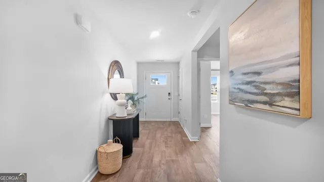 a view of a hallway with wooden floor and a bathroom