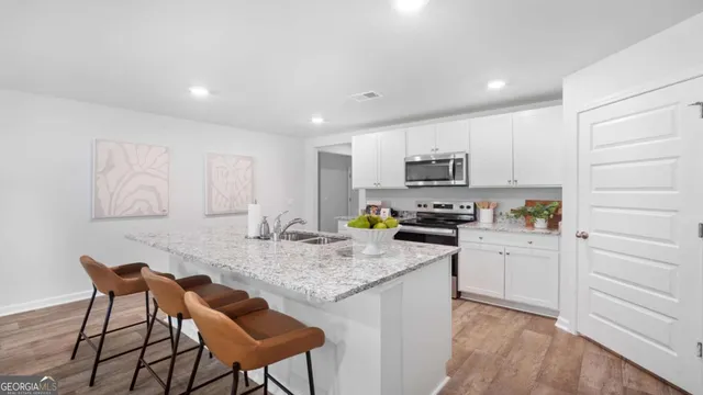 a kitchen with granite countertop white cabinets and stainless steel appliances