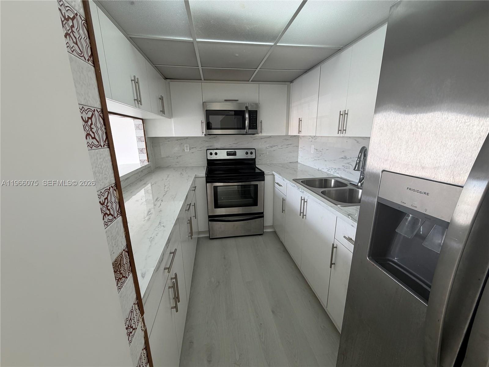 1104 West 44th Street, Unit 87 Hialeah, FL 33012 - Photo 6 of 13 a kitchen with a sink a microwave and cabinets