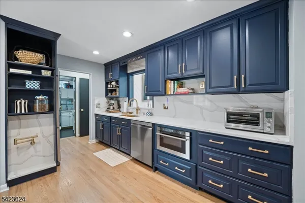 a kitchen with stainless steel appliances granite countertop wooden cabinets a stove top oven a sink and dishwasher