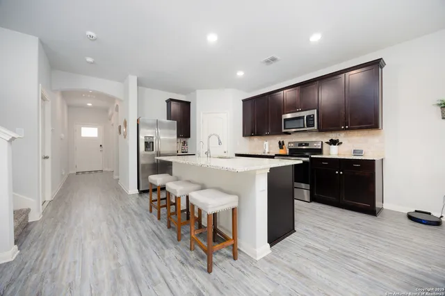 a large kitchen with stainless steel appliances wooden floor and a view of living room