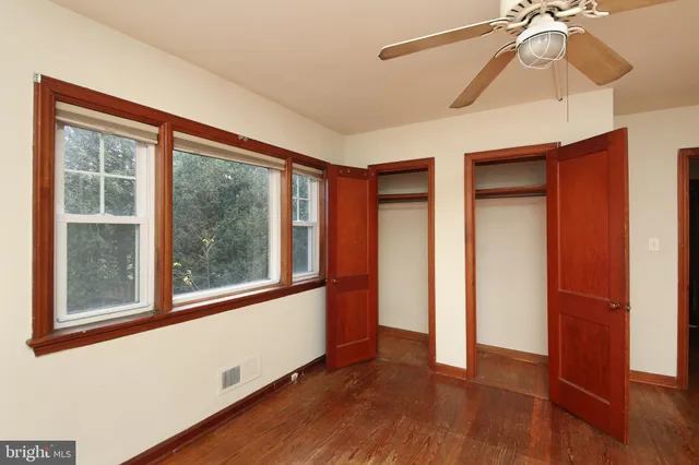 a view of empty room with wooden floor and fan