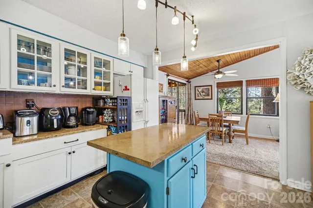 a kitchen with a stove a refrigerator and a dining table with wooden floor