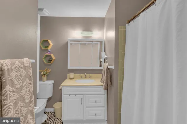 a bathroom with a granite countertop sink toilet and mirror