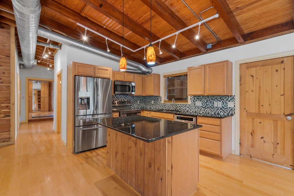 a kitchen with stainless steel appliances granite countertop a sink a stove and a refrigerator with cabinets