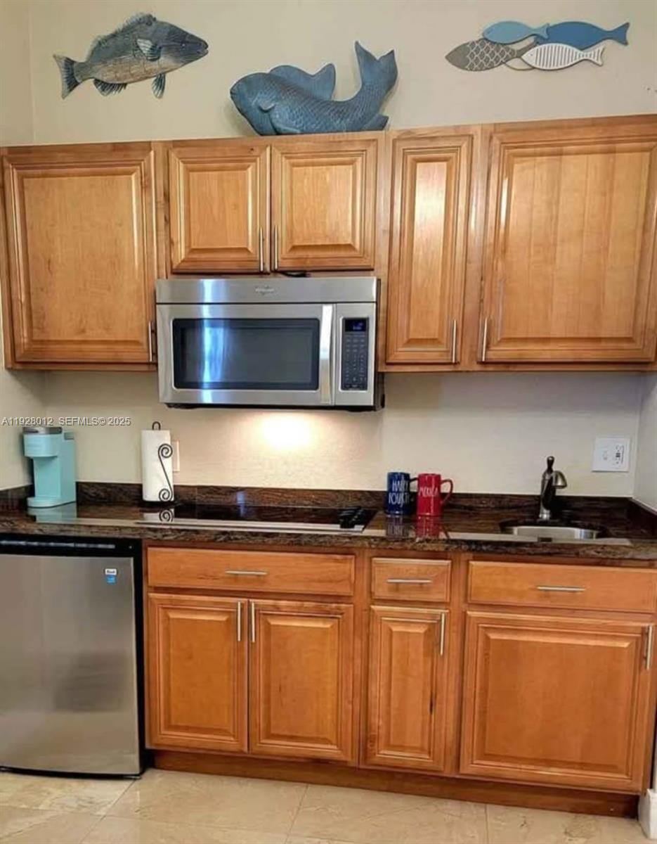 a kitchen with granite countertop a stove top oven microwave and cabinets