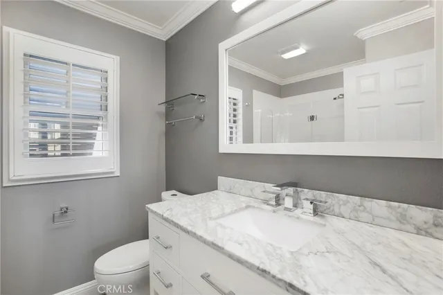 a bathroom with a granite countertop sink toilet a mirror and shower
