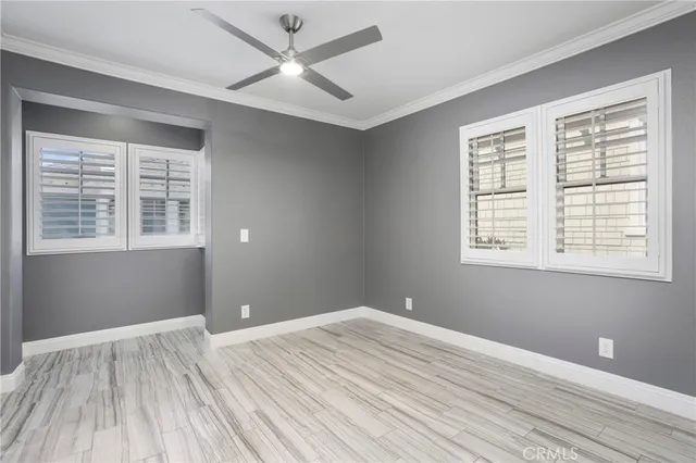 a view of empty room with wooden floor and fan