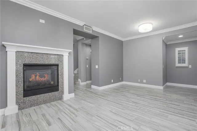 a view of an empty room with wooden floor fireplace and a window