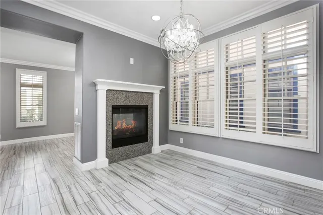 a view of an empty room with wooden floor fireplace and a window