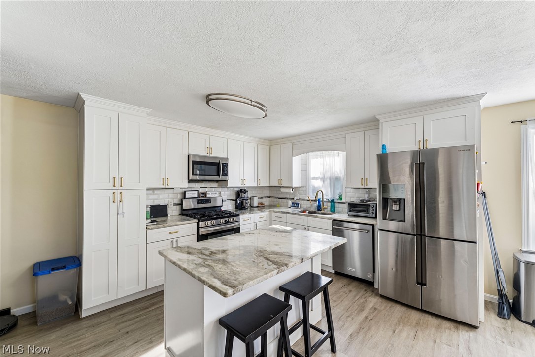 6711 Norwalk Road Medina, OH 44256 - Photo 9 of 46 Eat-in kitchen with white cabinetry, sink, stove, microwave, dishwasher, refrigerator, and center island