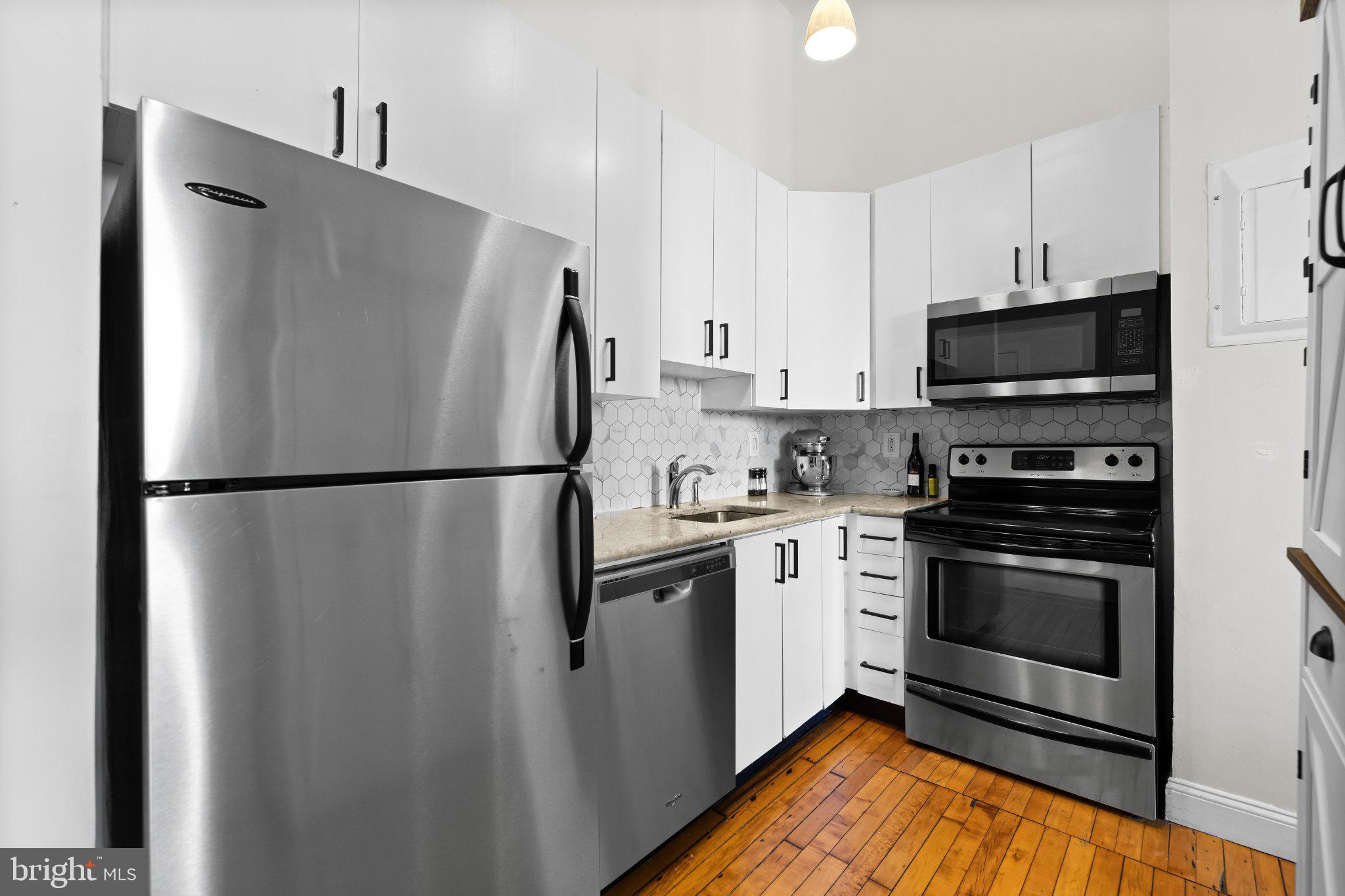 511 South Bond Street, Unit 302 Baltimore, MD 21231 - Photo 8 of 24 a kitchen with stainless steel appliances granite countertop a refrigerator a stove a sink and a microwave