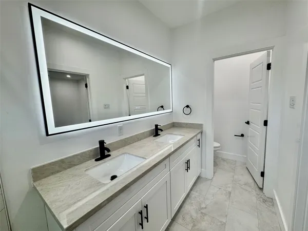 a bathroom with a granite countertop sink mirror and toilet