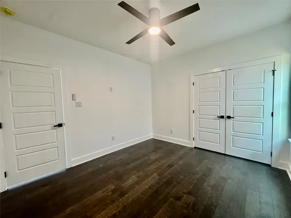 an empty room with wooden floor closet and windows