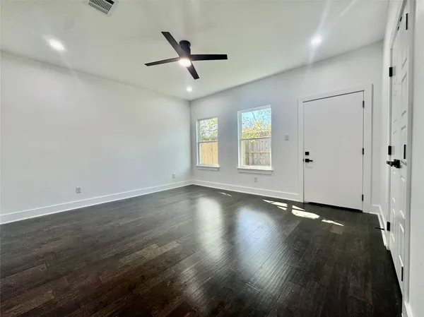 an empty room with wooden floor and windows