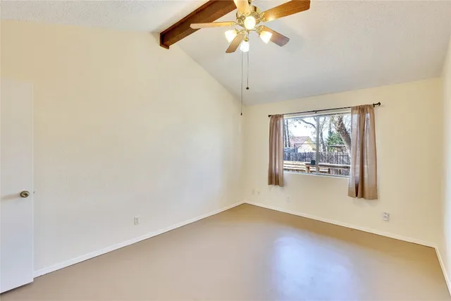 an empty room with chandelier fan and windows