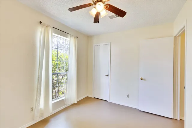 an empty room with windows and fan