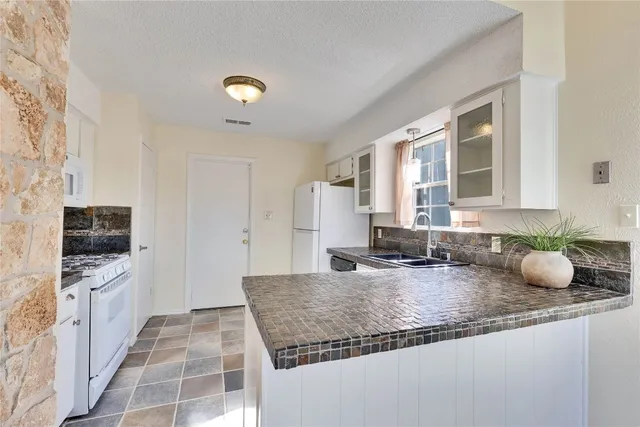 a kitchen with granite countertop a sink and a stove top oven
