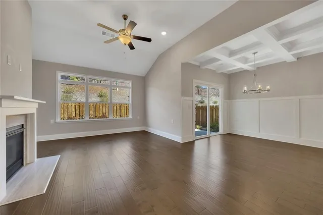 a view of a livingroom with a fireplace a chandelier fan and wooden floor