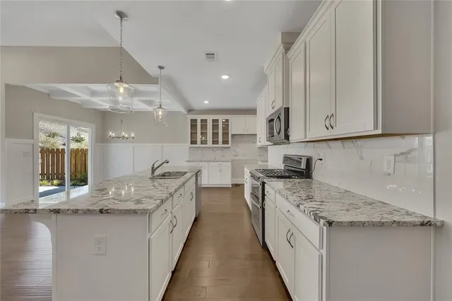 a kitchen with kitchen island a counter top space a sink stainless steel appliances and cabinets
