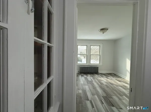 a view of an empty room with a window and wooden floor