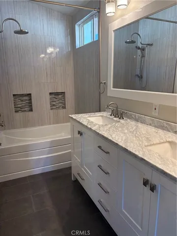 a bathroom with a granite countertop bathtub sink vanity mirror and toilet