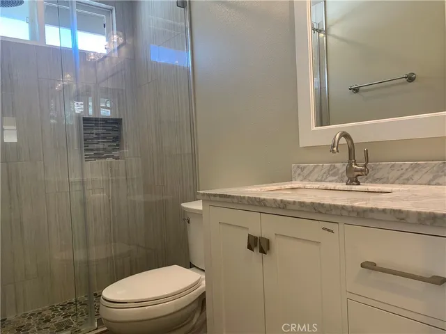 a bathroom with a granite countertop toilet and a shower