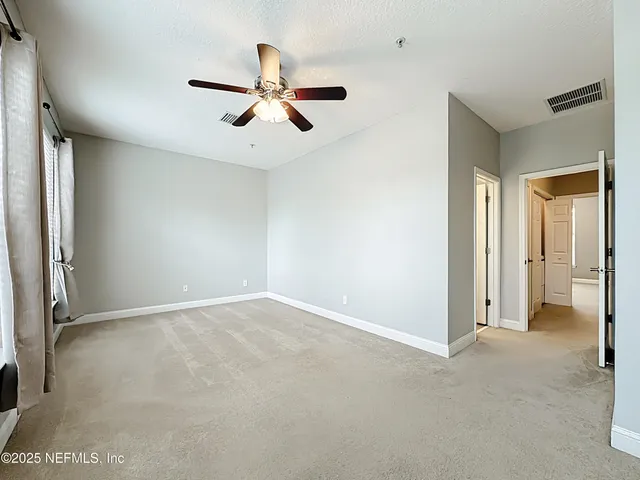 an empty room with ceiling fan and windows