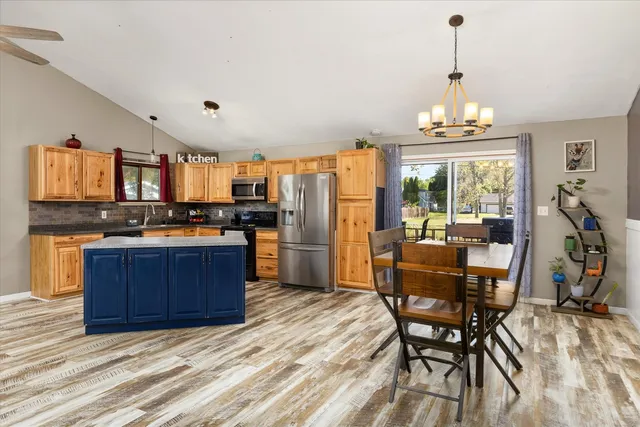 a kitchen with stainless steel appliances wooden floor dining table chairs and granite counter tops