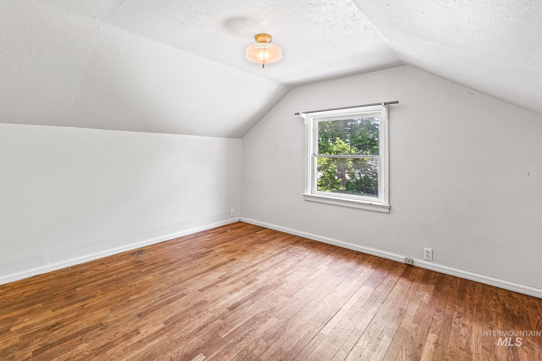404 North Allumbaugh Street Boise, ID 83704 - Photo 16 of 31 Bonus room featuring hardwood / wood-style flooring, vaulted ceiling, and a textured ceiling