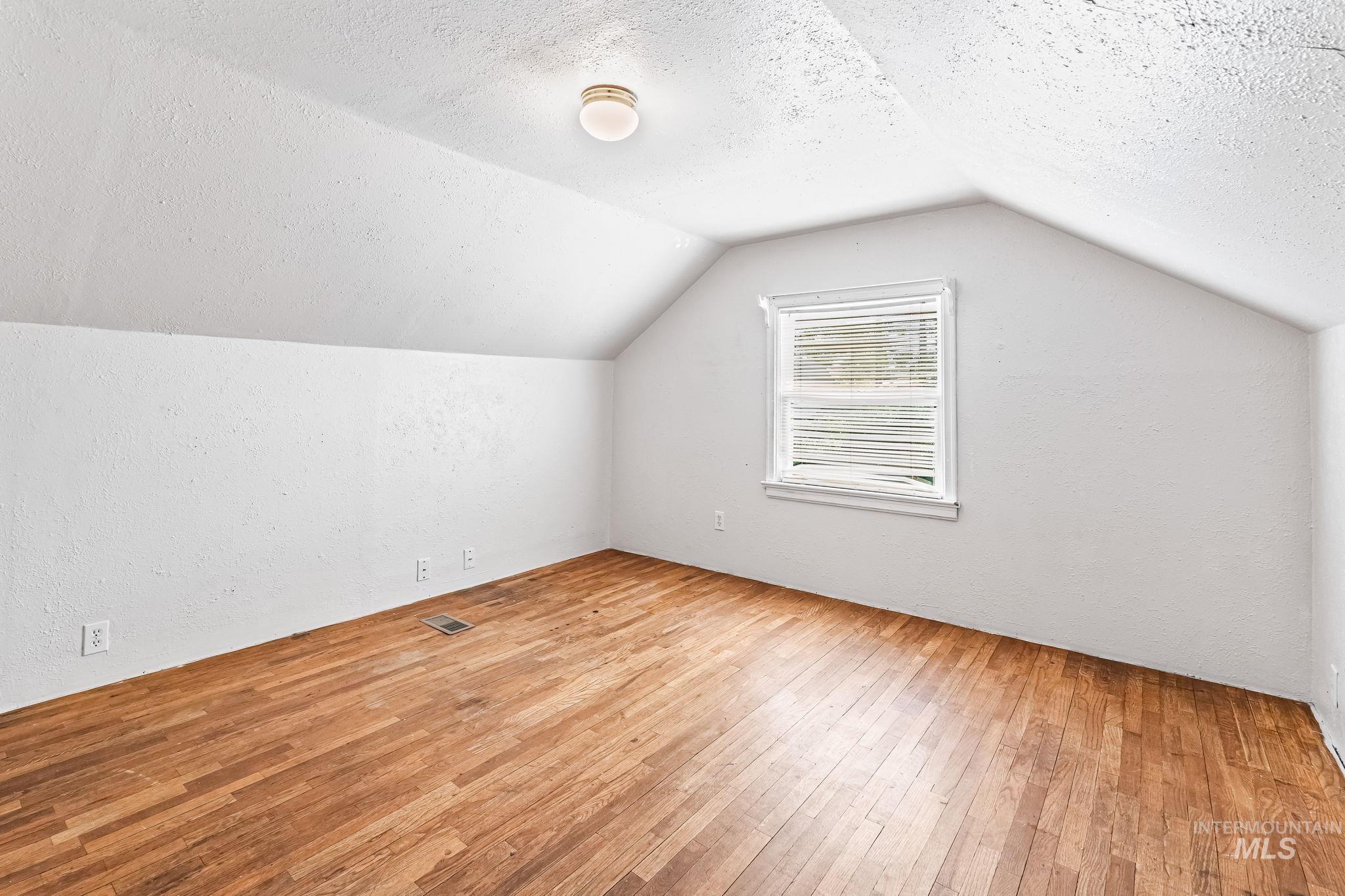 404 North Allumbaugh Street Boise, ID 83704 - Photo 17 of 31 Bonus room featuring a textured ceiling, wood-type flooring, vaulted ceiling, and a textured wall