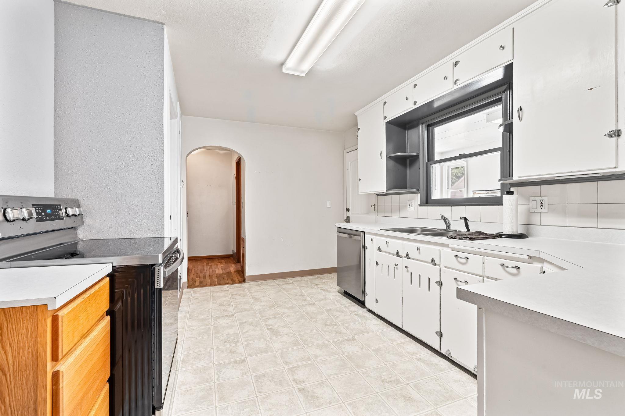 404 North Allumbaugh Street Boise, ID 83704 - Photo 23 of 31 Kitchen with stainless steel appliances, arched walkways, light countertops, decorative backsplash, and light floors