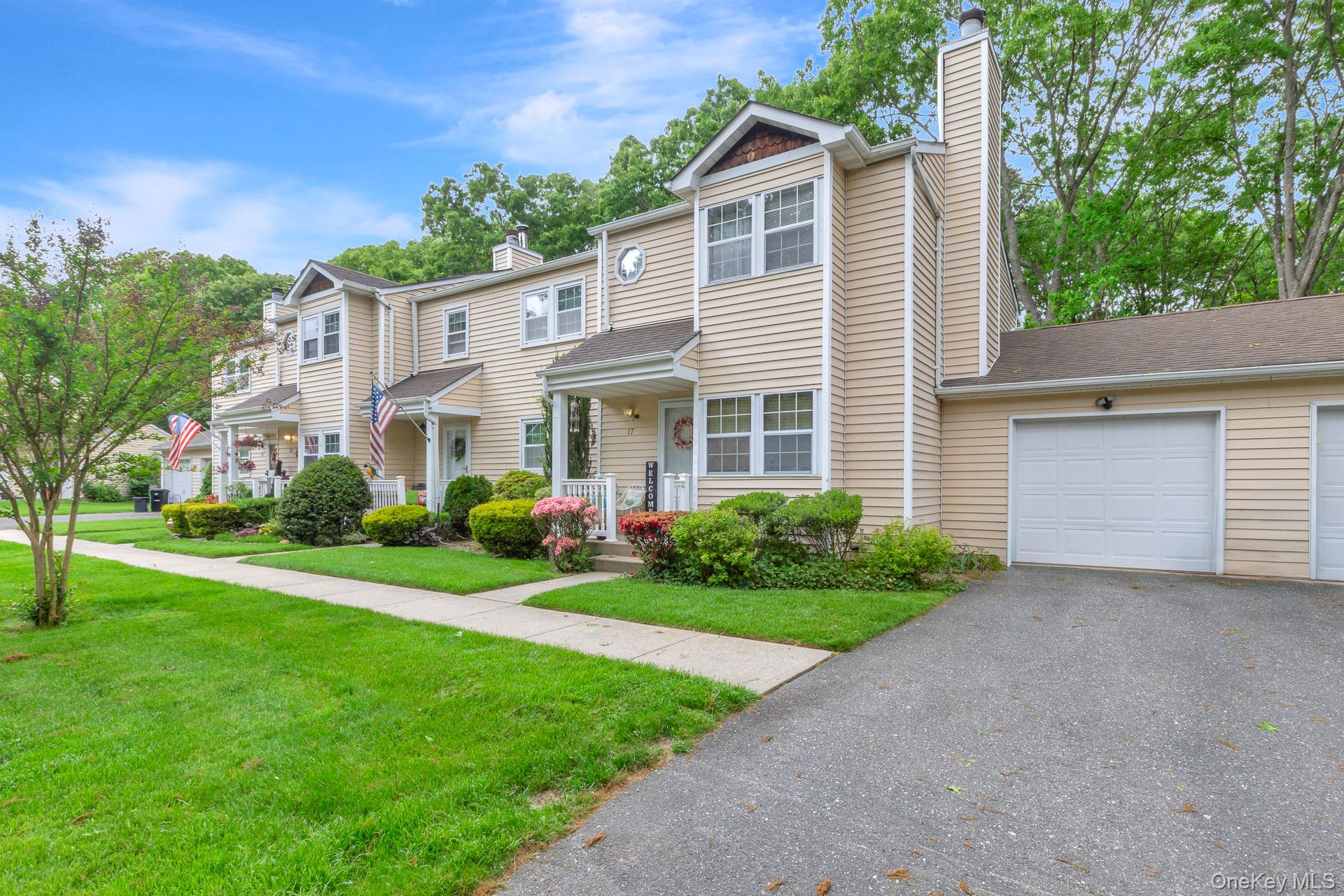 17 Stone Commons Yaphank, NY 11980 - Photo 7 of 31 Townhome exterior featuring light-colored siding, a covered entry porch, and a two-story architectural design