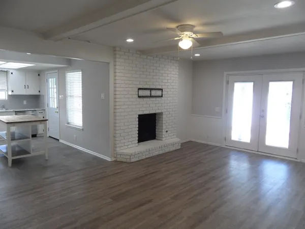 a view of an empty room with window and wooden floor
