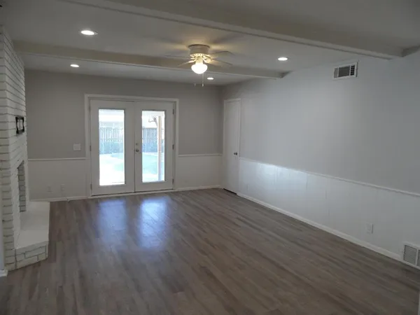 an empty room with wooden floor and windows