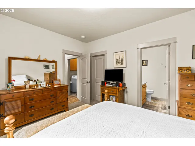 a bedroom with a bed and a flat tv screen on dresser