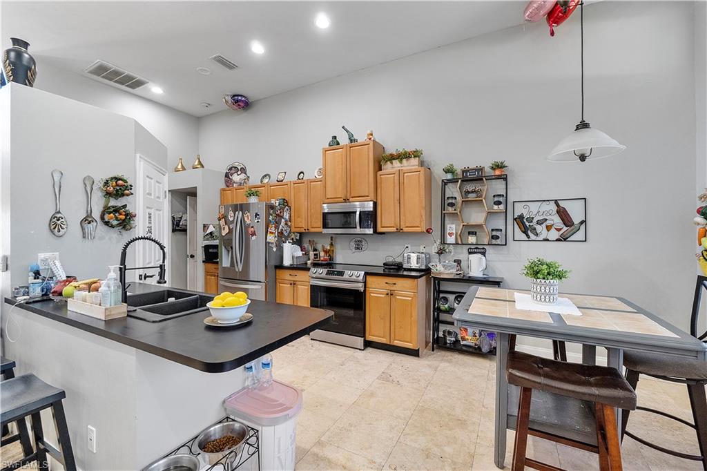 8081 Kansas Road Fort Myers, FL 33967 - Photo 15 of 21 a kitchen with a sink a stove and chairs with wooden floor