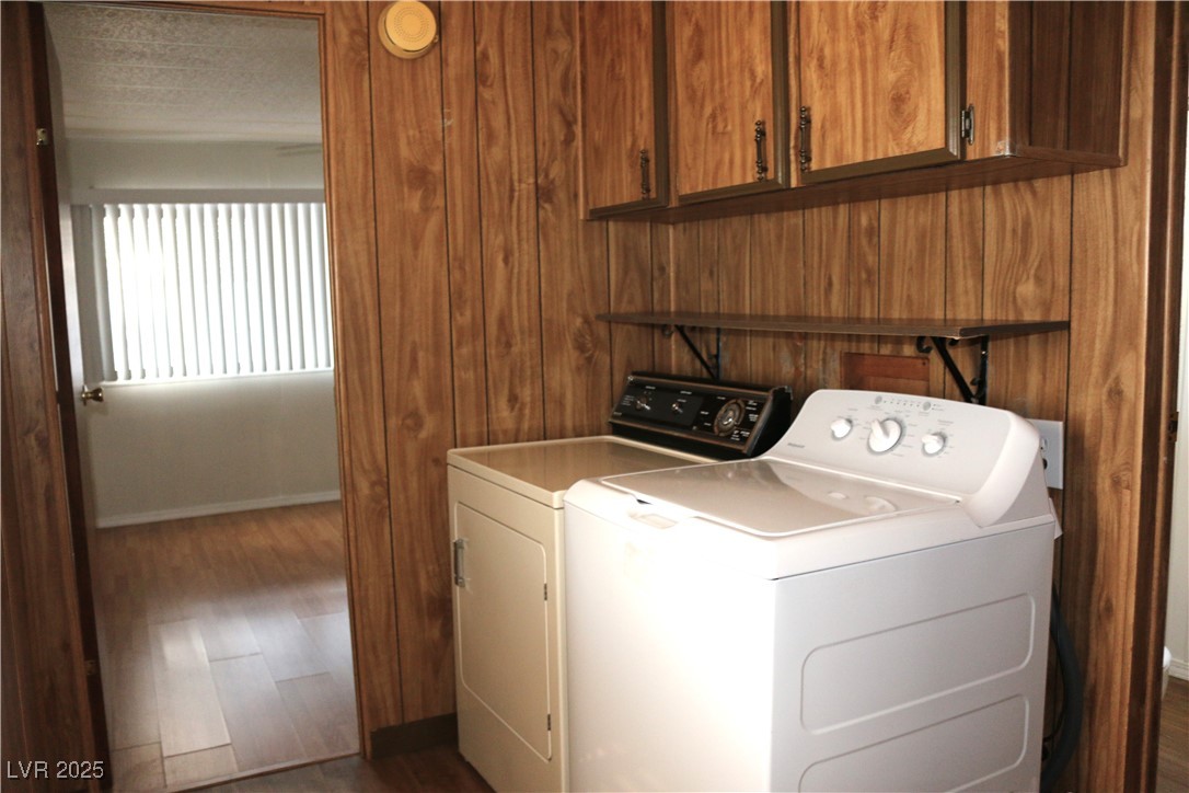 4633 Royal Ridge Boulevard Las Vegas, NV 89103 - Photo 11 of 13 Laundry room featuring dark wood-type flooring, cabinet space, separate washer and dryer, and wooden walls