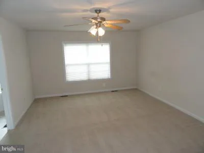 an empty room with a window and a chandelier fan