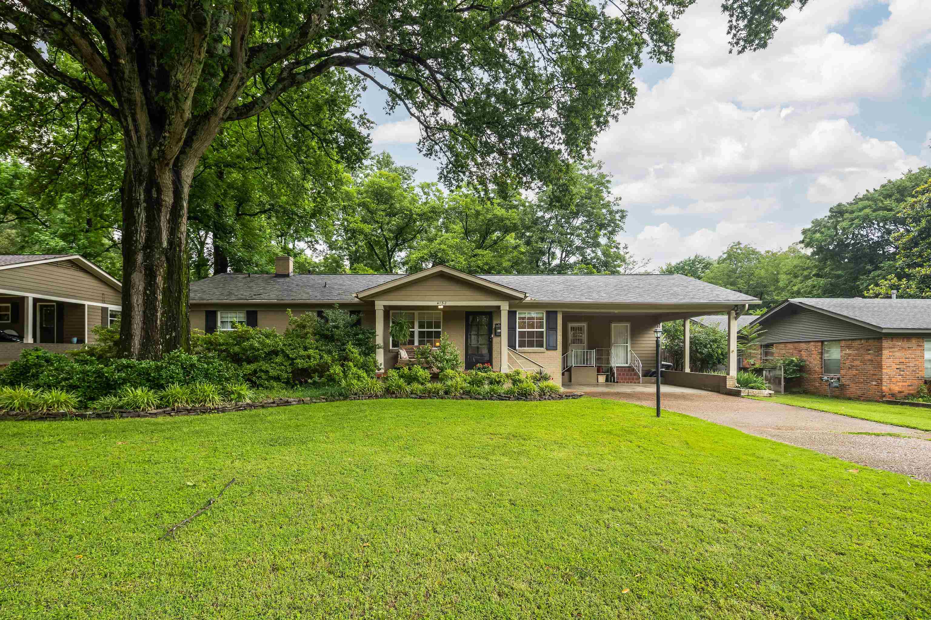Single story home with covered porch, asphalt driveway, a front yard, a chimney, and a carport