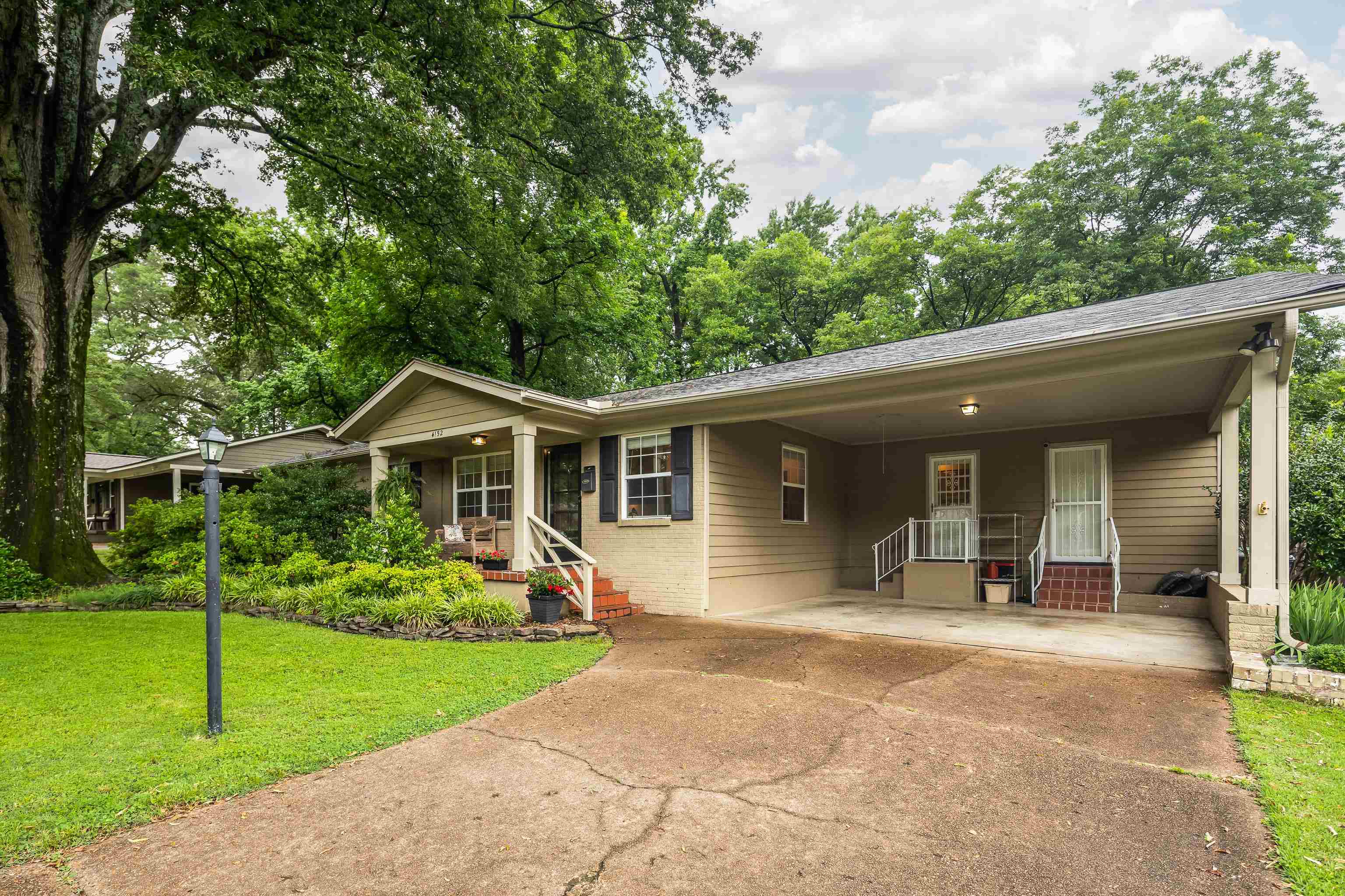 Ranch-style home featuring a carport, a front yard, concrete driveway, and a porch
