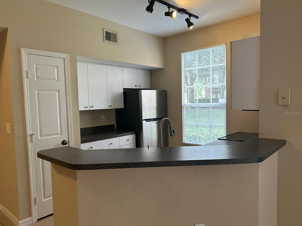 6408 Raleigh Street, Unit 2403 Orlando, FL 32835 - Photo 5 of 18 a counter top space with stainless steel appliances granite countertop a sink a refrigerator and a granite counter tops
