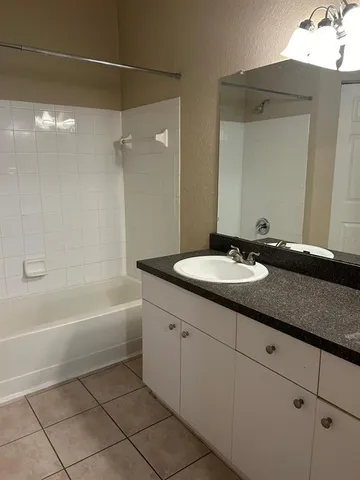 a bathroom with a granite countertop sink a mirror and a bathtub