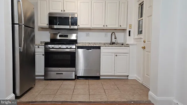 a kitchen with stainless steel appliances granite countertop a refrigerator stove and white cabinets