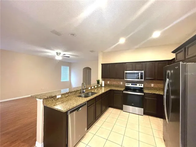 a kitchen with stainless steel appliances granite countertop a sink stove and refrigerator