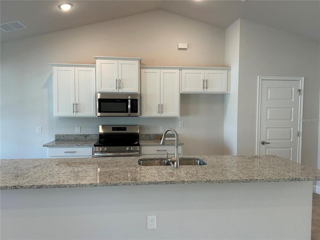 2679 Englewood Road Venice, FL 34293 - Photo 6 of 14 a kitchen with stainless steel appliances granite countertop a sink a stove a microwave and a granite counter tops