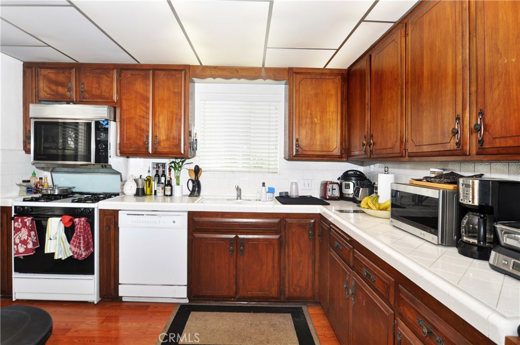 217 10th Street, Unit 4 Seal Beach, CA 90740 - Photo 5 of 45 a kitchen with stainless steel appliances granite countertop a stove a sink dishwasher and a microwave oven with cabinets