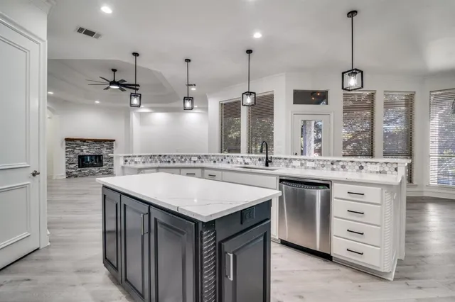 a kitchen with stainless steel appliances granite countertop a sink a stove and a wooden floor