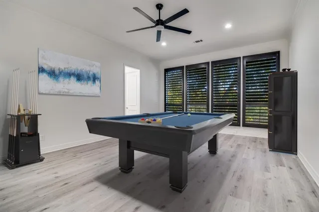 a room with wooden floor pool table and windows