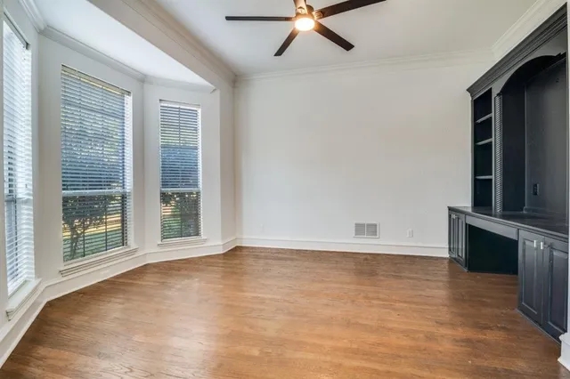 a view of an empty room with a window and wooden floor